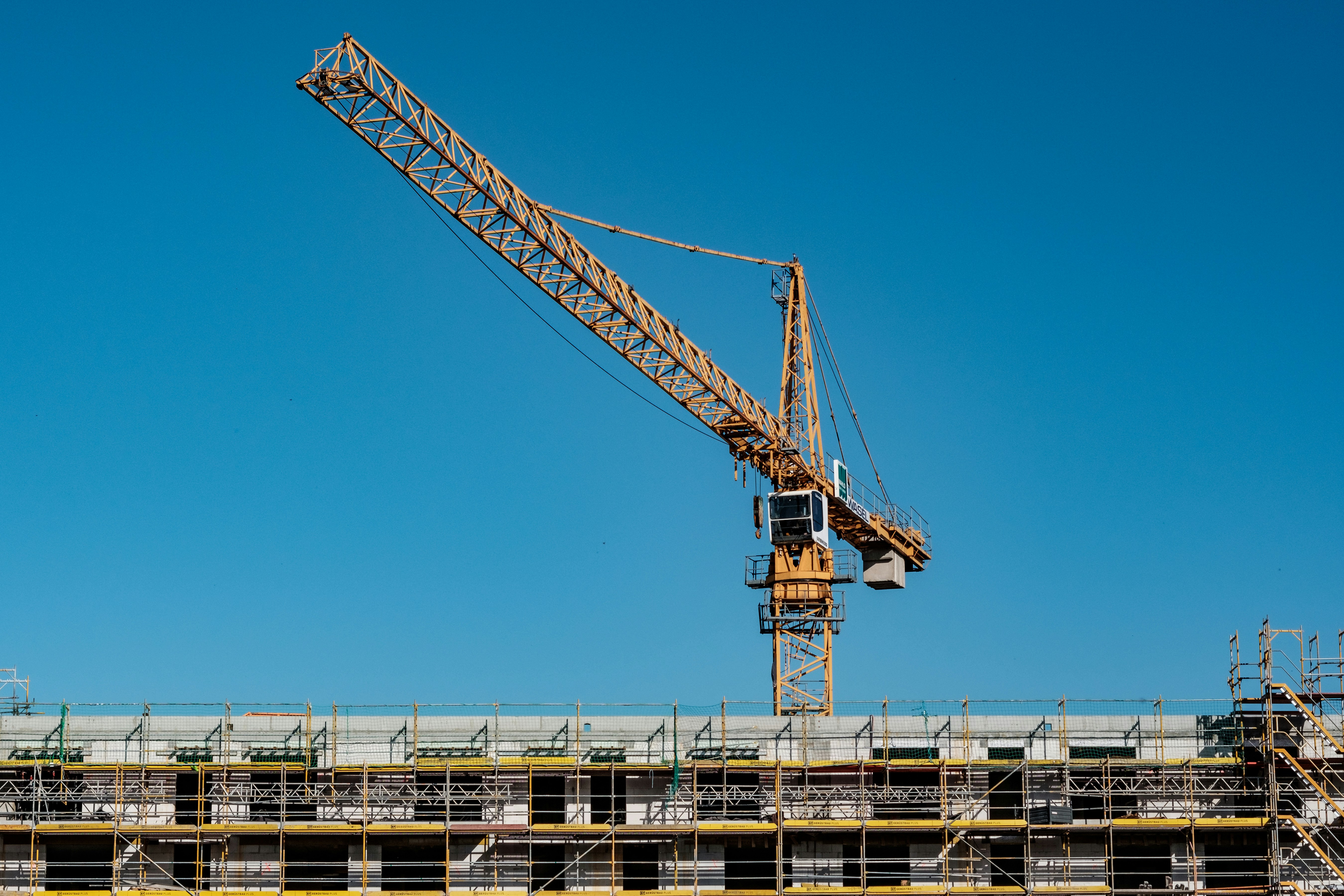 yellow crane on construction site against blue background