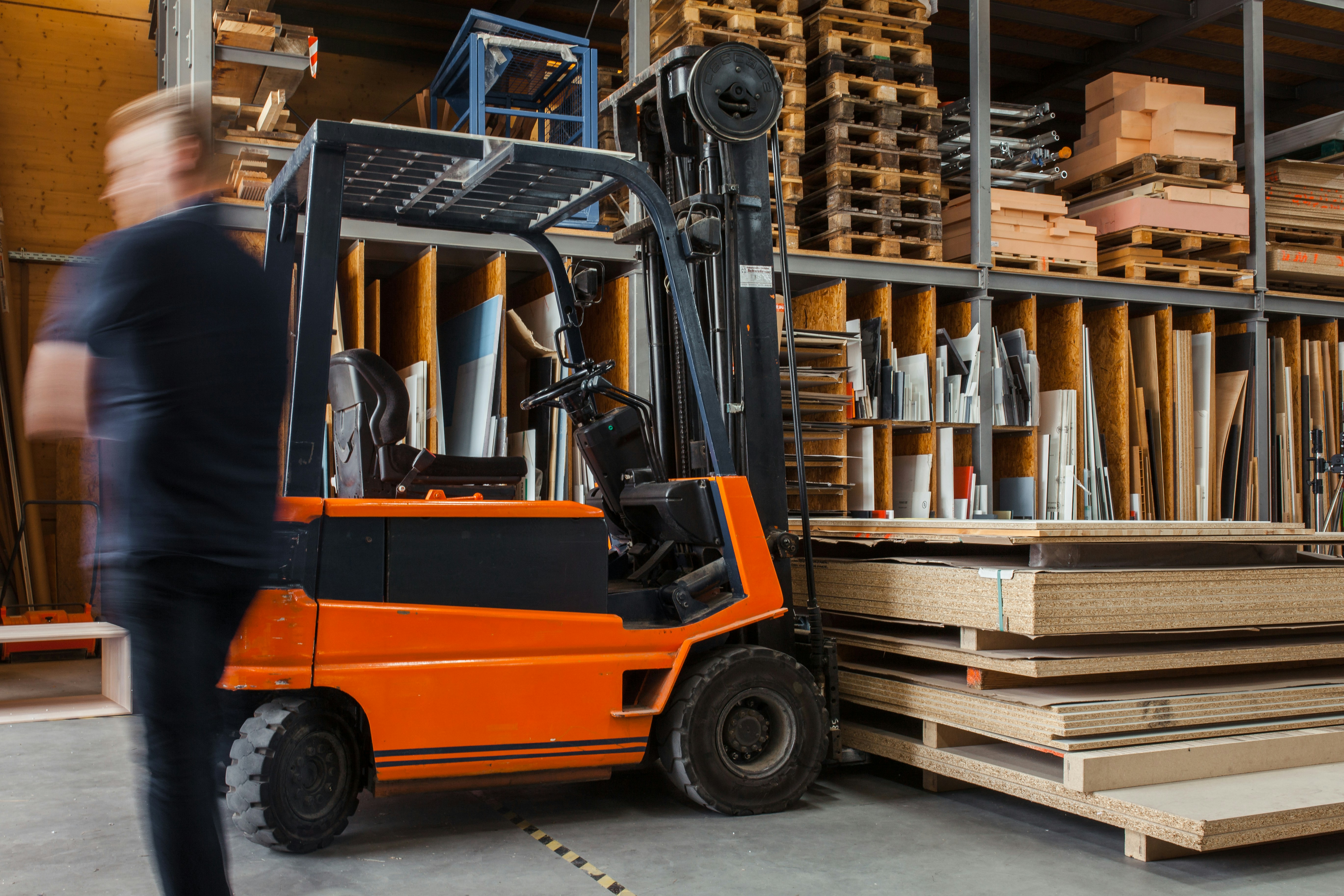 fork lift in a factory next to a factory worker
